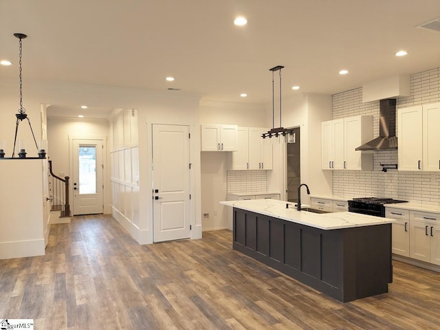 kitchen featuring dark wood-style floors, black gas range, wall chimney exhaust hood, and a sink