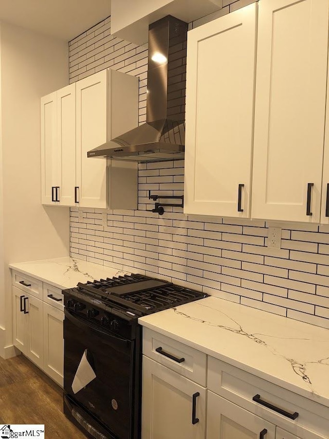 kitchen featuring tasteful backsplash, black gas range, white cabinets, and wall chimney range hood