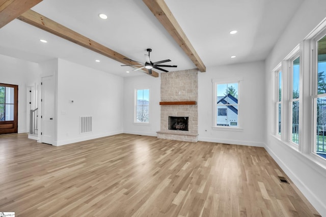 unfurnished living room featuring beamed ceiling, baseboards, visible vents, and a fireplace