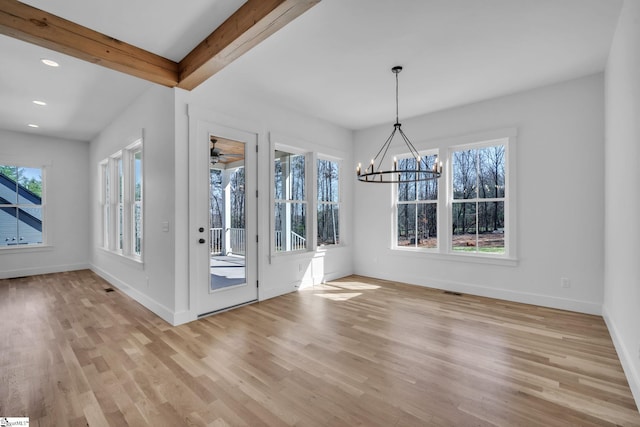 unfurnished dining area featuring light wood finished floors, beamed ceiling, a chandelier, and baseboards