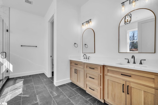 bathroom with double vanity, marble finish floor, baseboards, and a sink