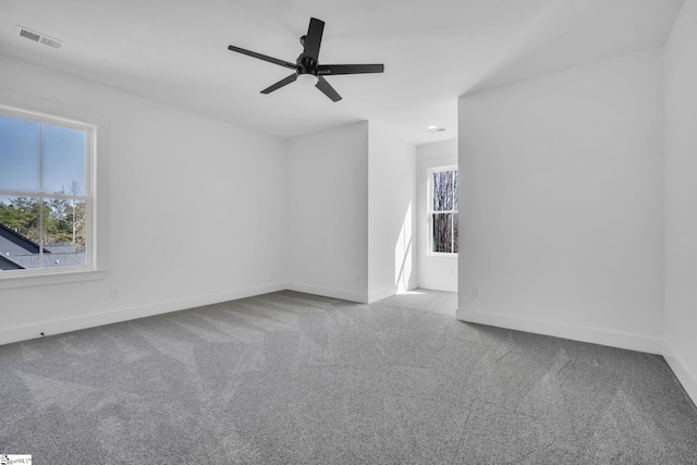 carpeted spare room with visible vents, ceiling fan, and baseboards