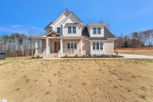 view of front of house featuring board and batten siding, brick siding, and a porch