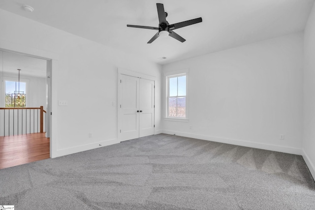 unfurnished room with a wealth of natural light, baseboards, carpet floors, and ceiling fan