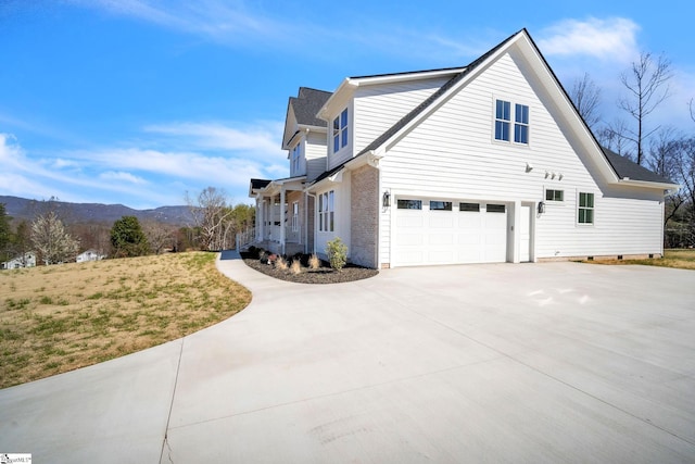 view of side of home featuring brick siding, a mountain view, driveway, and a garage