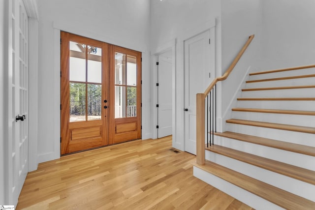 foyer entrance featuring visible vents, french doors, light wood-type flooring, and stairs