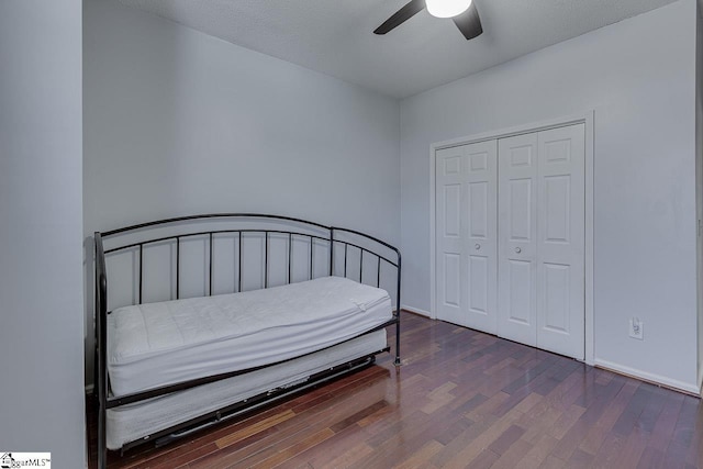 bedroom with a ceiling fan, wood finished floors, baseboards, and a closet