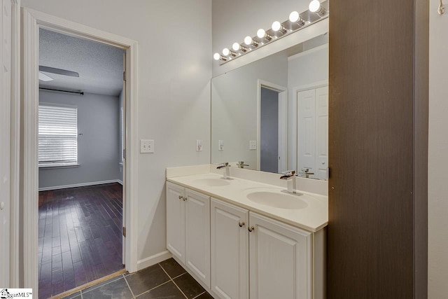 bathroom with a textured ceiling, tile patterned floors, double vanity, and a sink