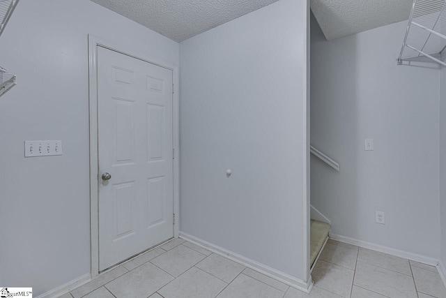 foyer featuring light tile patterned floors, a textured ceiling, stairs, and baseboards