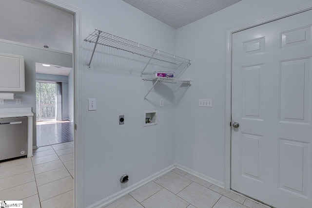 washroom with electric dryer hookup, washer hookup, a textured ceiling, light tile patterned floors, and laundry area