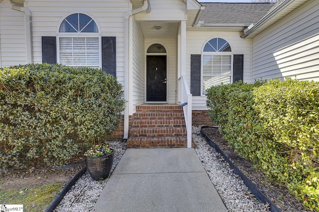 entrance to property featuring a shingled roof