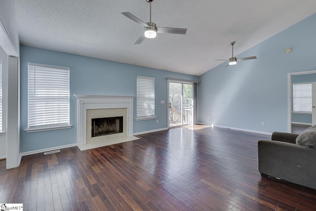 unfurnished living room with wood finished floors, visible vents, a premium fireplace, lofted ceiling, and ceiling fan