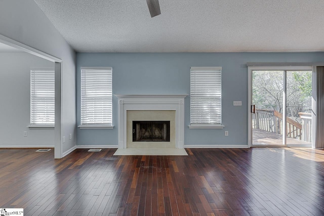 unfurnished living room with baseboards, a fireplace with flush hearth, a textured ceiling, and wood-type flooring