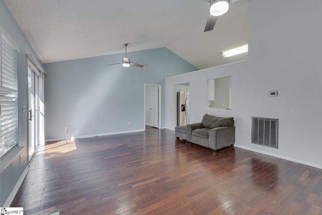 living area featuring visible vents, baseboards, vaulted ceiling, wood finished floors, and a ceiling fan