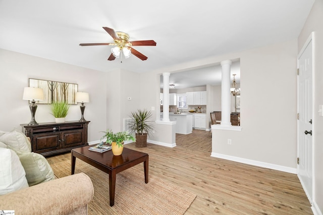 living room featuring baseboards, light wood finished floors, ceiling fan, and ornate columns