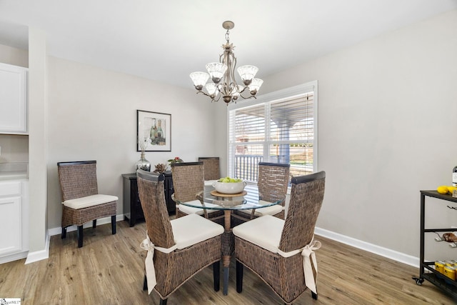 dining space featuring a notable chandelier, baseboards, and light wood-style floors