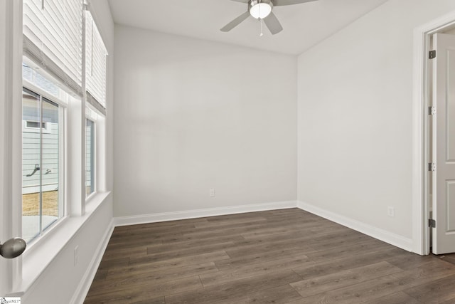 spare room with baseboards, dark wood-style flooring, and ceiling fan