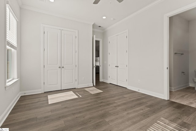 unfurnished bedroom with connected bathroom, baseboards, wood finished floors, and crown molding