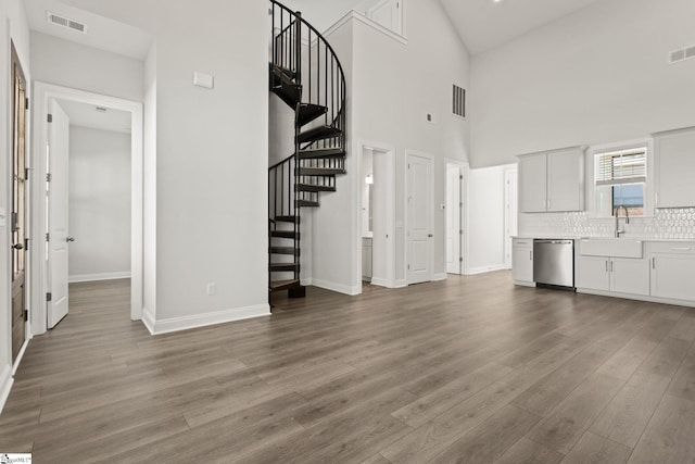 unfurnished living room with stairs, wood finished floors, visible vents, and a sink