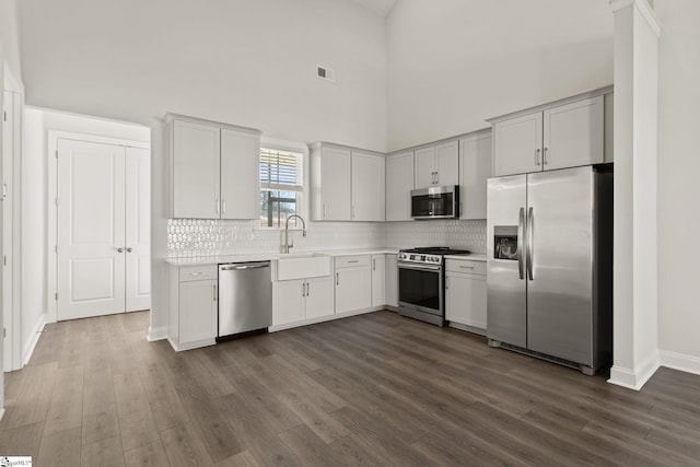 kitchen with visible vents, a sink, light countertops, dark wood-type flooring, and appliances with stainless steel finishes