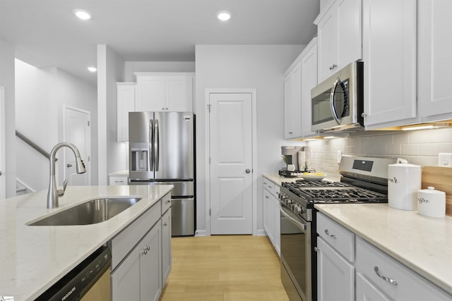 kitchen with a sink, recessed lighting, stainless steel appliances, white cabinets, and decorative backsplash