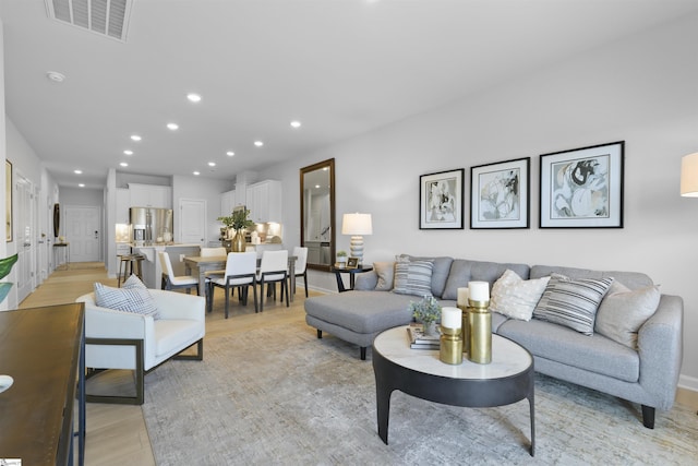 living area with recessed lighting, visible vents, and light wood finished floors