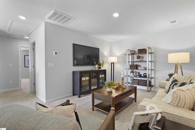 living room with visible vents, light colored carpet, attic access, and baseboards