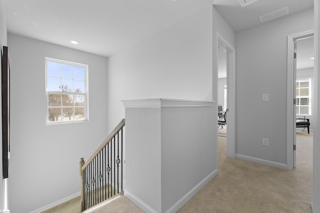 hallway featuring visible vents, an upstairs landing, carpet, and a healthy amount of sunlight