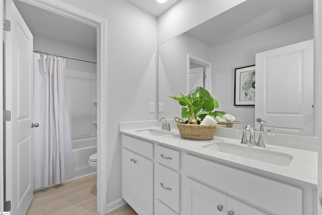 bathroom featuring a sink, toilet, wood finished floors, and double vanity