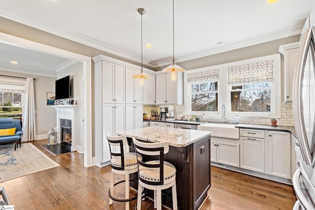 kitchen featuring a sink, appliances with stainless steel finishes, dark wood finished floors, and ornamental molding