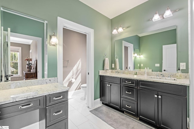 bathroom featuring a sink, baseboards, toilet, and double vanity