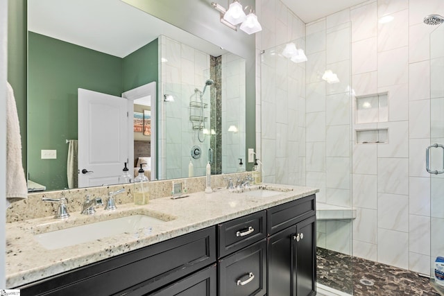 bathroom featuring double vanity, a stall shower, and a sink