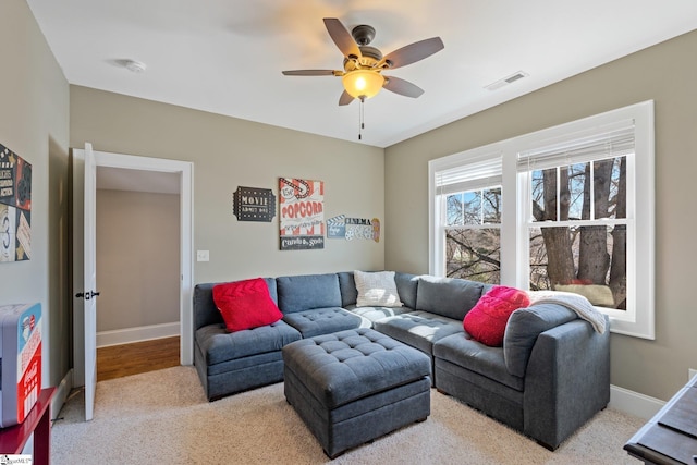 living room featuring baseboards, visible vents, and ceiling fan