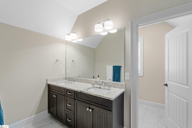 full bath featuring vaulted ceiling, marble finish floor, baseboards, and a sink