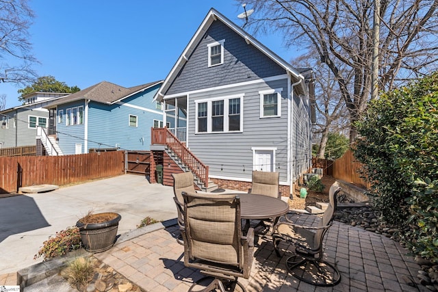 rear view of property featuring stairway, a patio, outdoor dining area, and fence