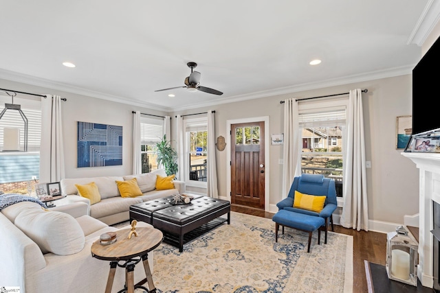 living room featuring a fireplace with flush hearth, plenty of natural light, crown molding, and dark wood-type flooring