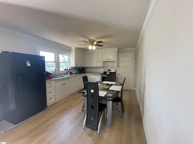 kitchen with stainless steel range with electric stovetop, white cabinets, freestanding refrigerator, and a sink