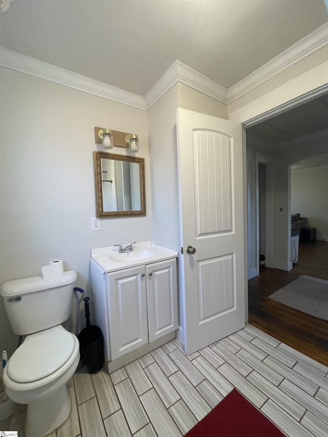 bathroom with ornamental molding, toilet, vanity, and wood tiled floor