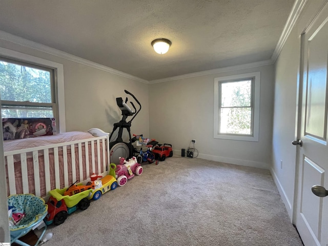 recreation room with a textured ceiling, carpet flooring, baseboards, and ornamental molding