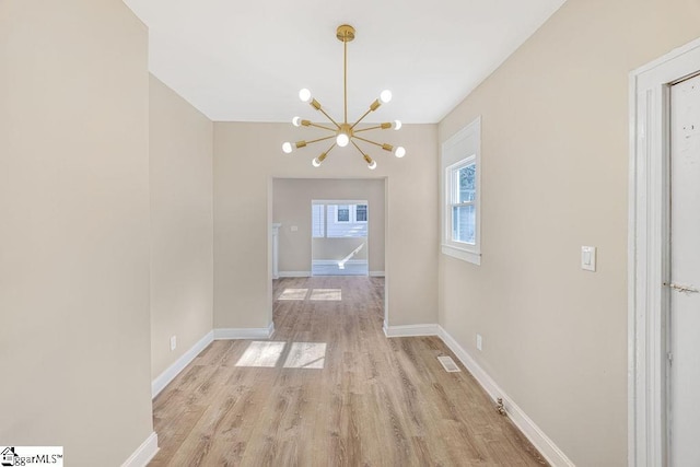 unfurnished dining area with a notable chandelier, visible vents, light wood-type flooring, and baseboards