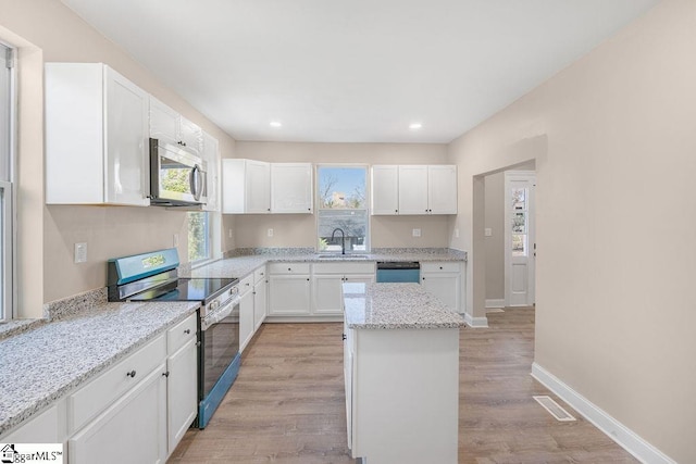 kitchen with visible vents, light wood-style floors, white cabinets, stainless steel appliances, and a sink