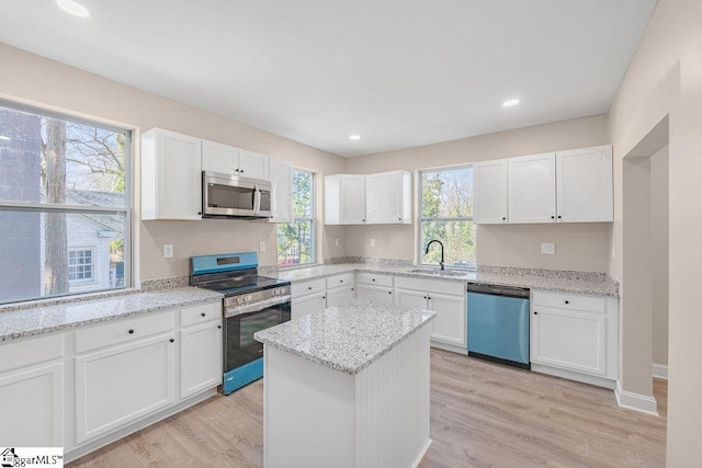 kitchen with white cabinets, light wood-type flooring, appliances with stainless steel finishes, and a sink