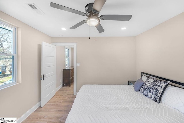 bedroom featuring visible vents, multiple windows, light wood-style floors, and baseboards