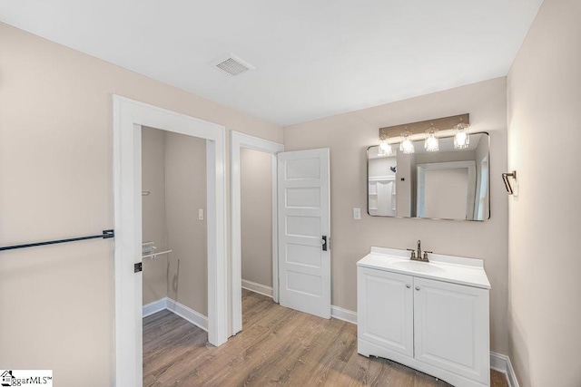 bathroom featuring vanity, wood finished floors, visible vents, and baseboards