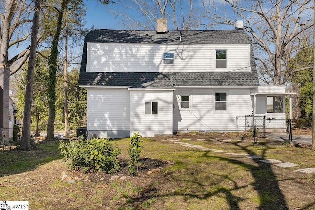 rear view of house featuring fence, roof with shingles, a sunroom, a chimney, and a lawn