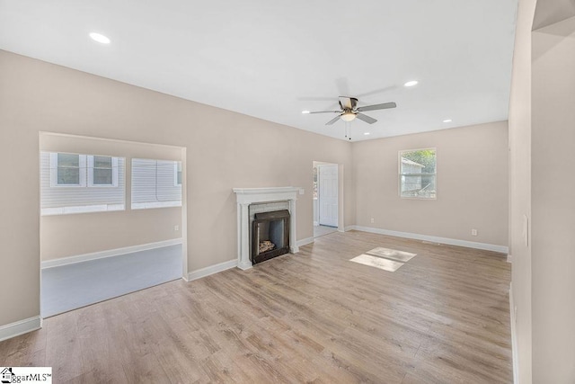 unfurnished living room with light wood finished floors, baseboards, recessed lighting, a fireplace, and a ceiling fan