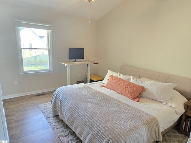 bedroom featuring visible vents, baseboards, and wood finished floors