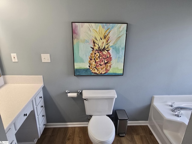 bathroom with baseboards, toilet, wood finished floors, and vanity