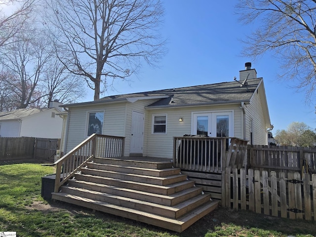 back of property with a lawn, a fenced backyard, a chimney, and a wooden deck