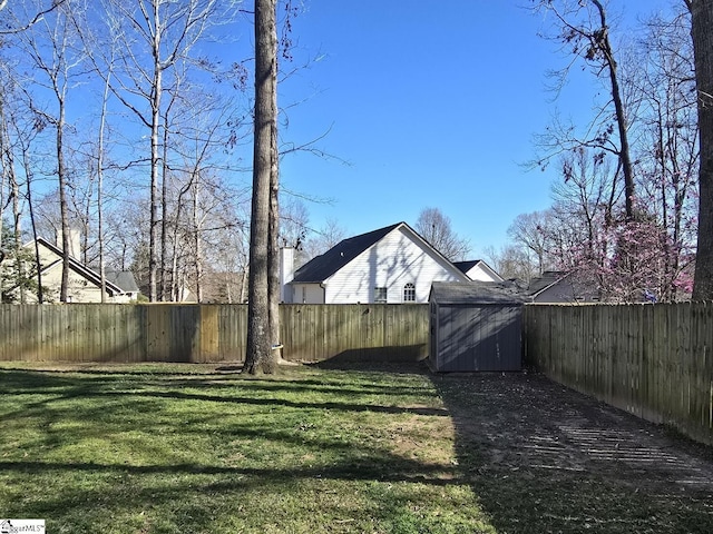 view of yard with an outbuilding, a storage unit, and a fenced backyard